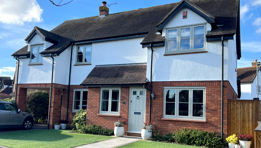 Two-story house with white stucco upper and red brick lower sections; green lawn, car parked in front.