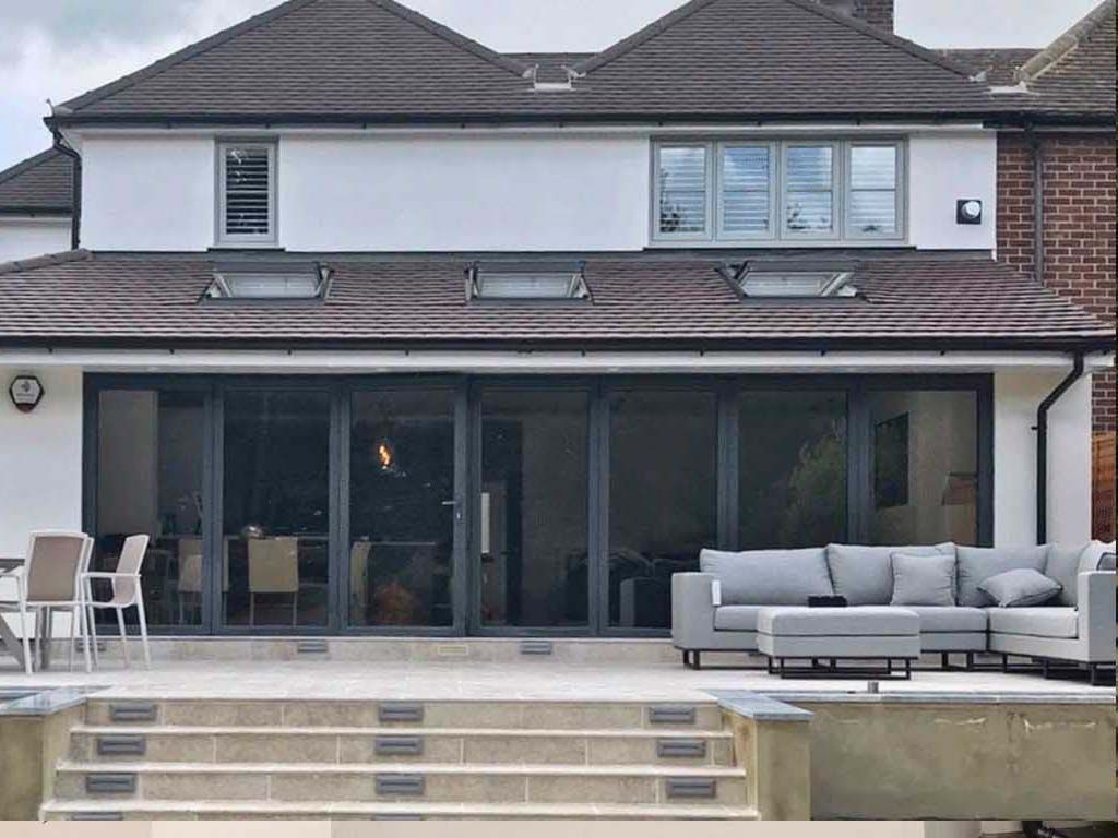 The back of a house with a patio and a couch in front of it.