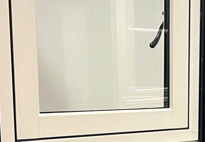 White window with a black handle against a white wall.