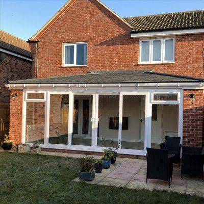 A red brick house with a large glass extension  with a warm roof.
