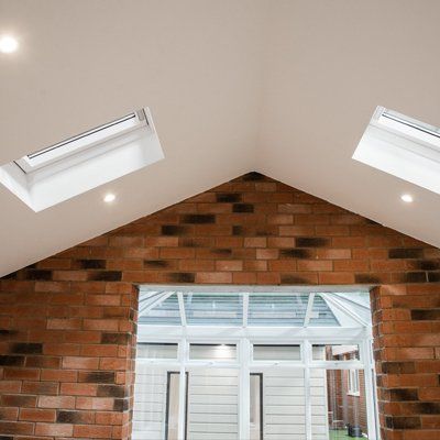 A room with a brick wall and two skylights on the ceiling.