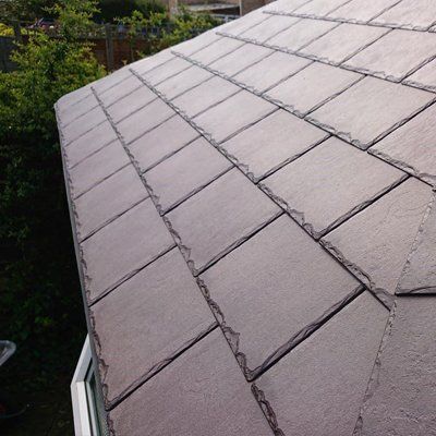 A close up of a warm roof with trees in the background