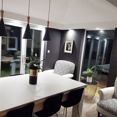 A dining room with a table and chairs and a potted plant on the table.