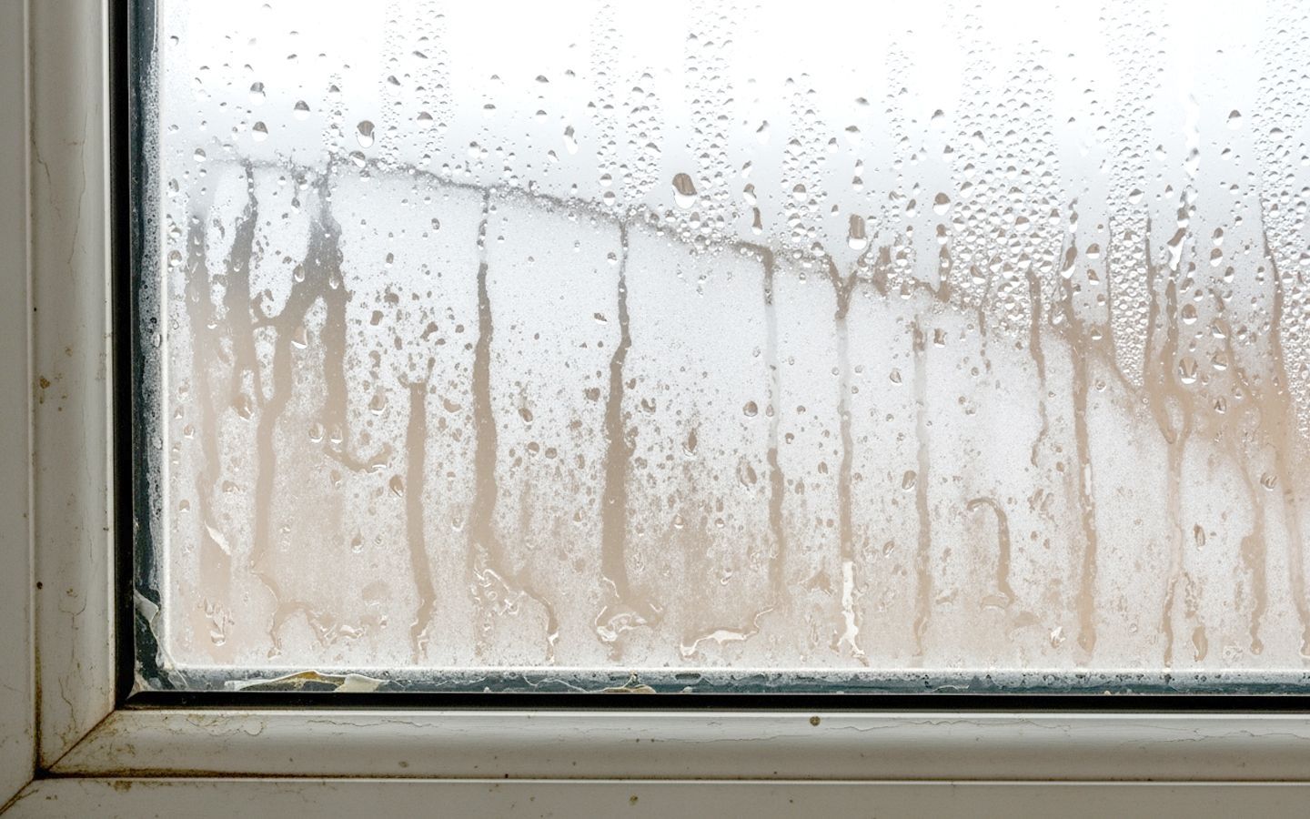 Window with condensation and streaks on the glass, set in a white frame.