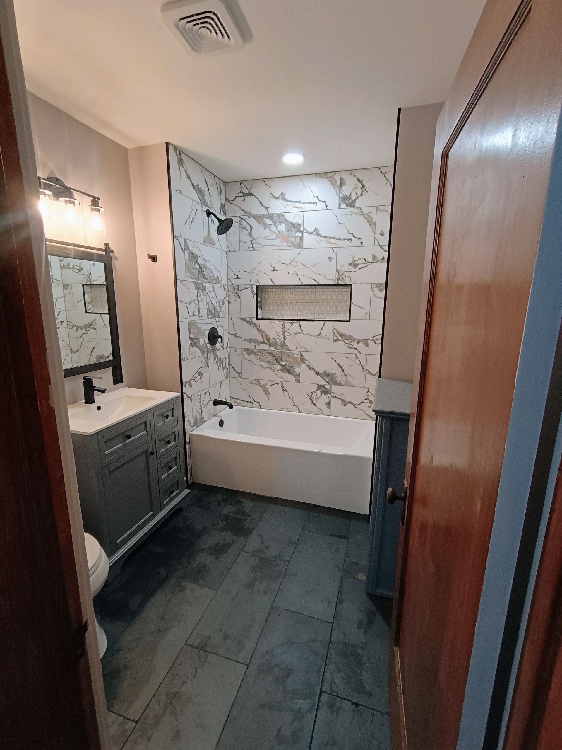 A bathroom with a bathtub , sink and mirror.