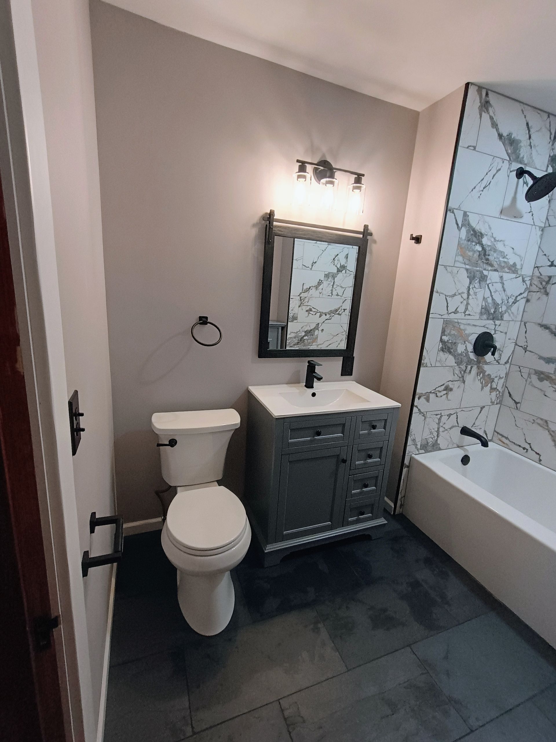 A bathroom with a toilet , sink , mirror and bathtub.