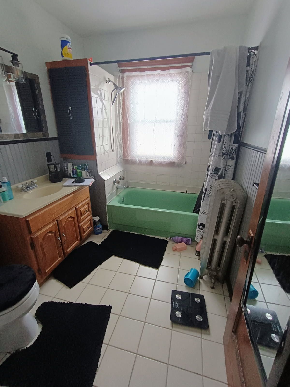 A bathroom with a green tub , toilet , sink and mirror.