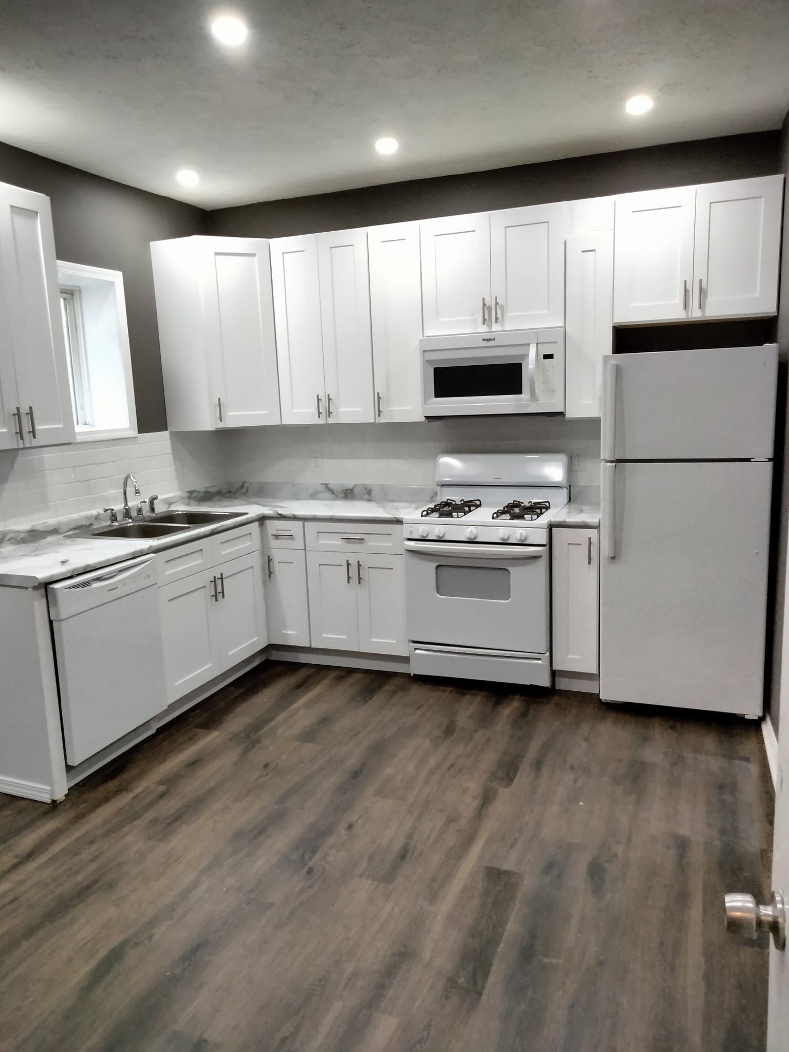 A kitchen with white cabinets and a refrigerator
