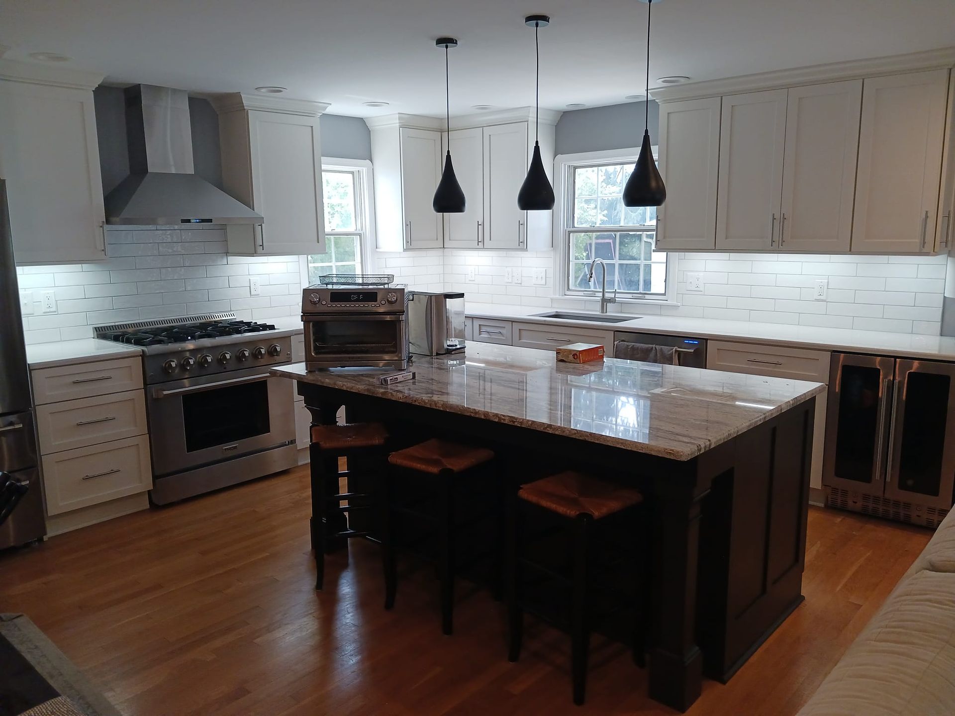A kitchen with white cabinets , stainless steel appliances , granite counter tops and a large island.