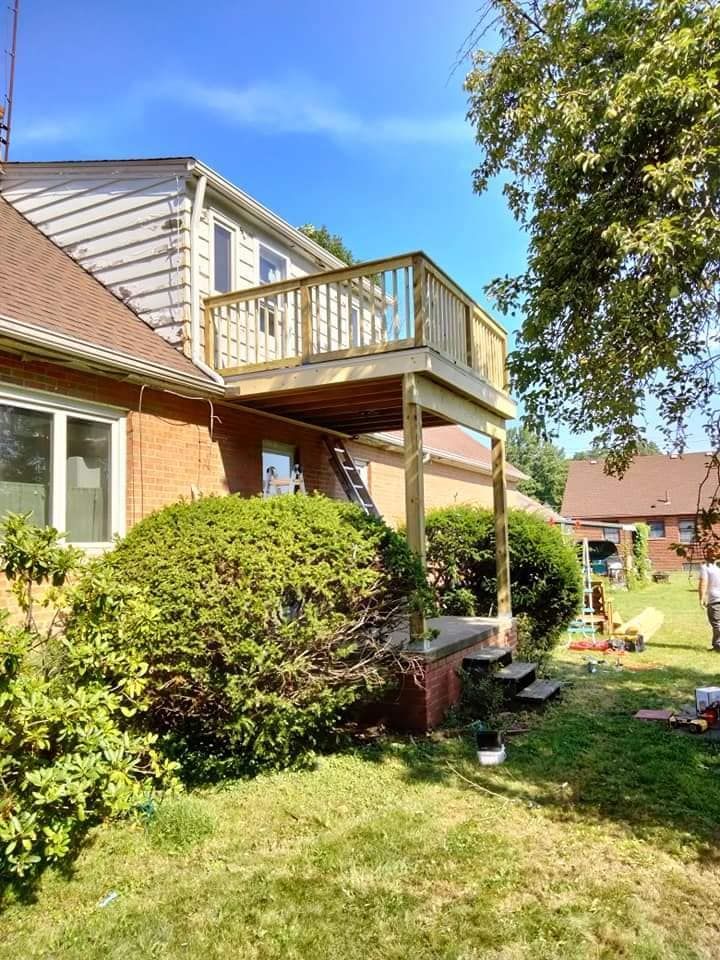 A wooden deck is being built in the backyard of a house.