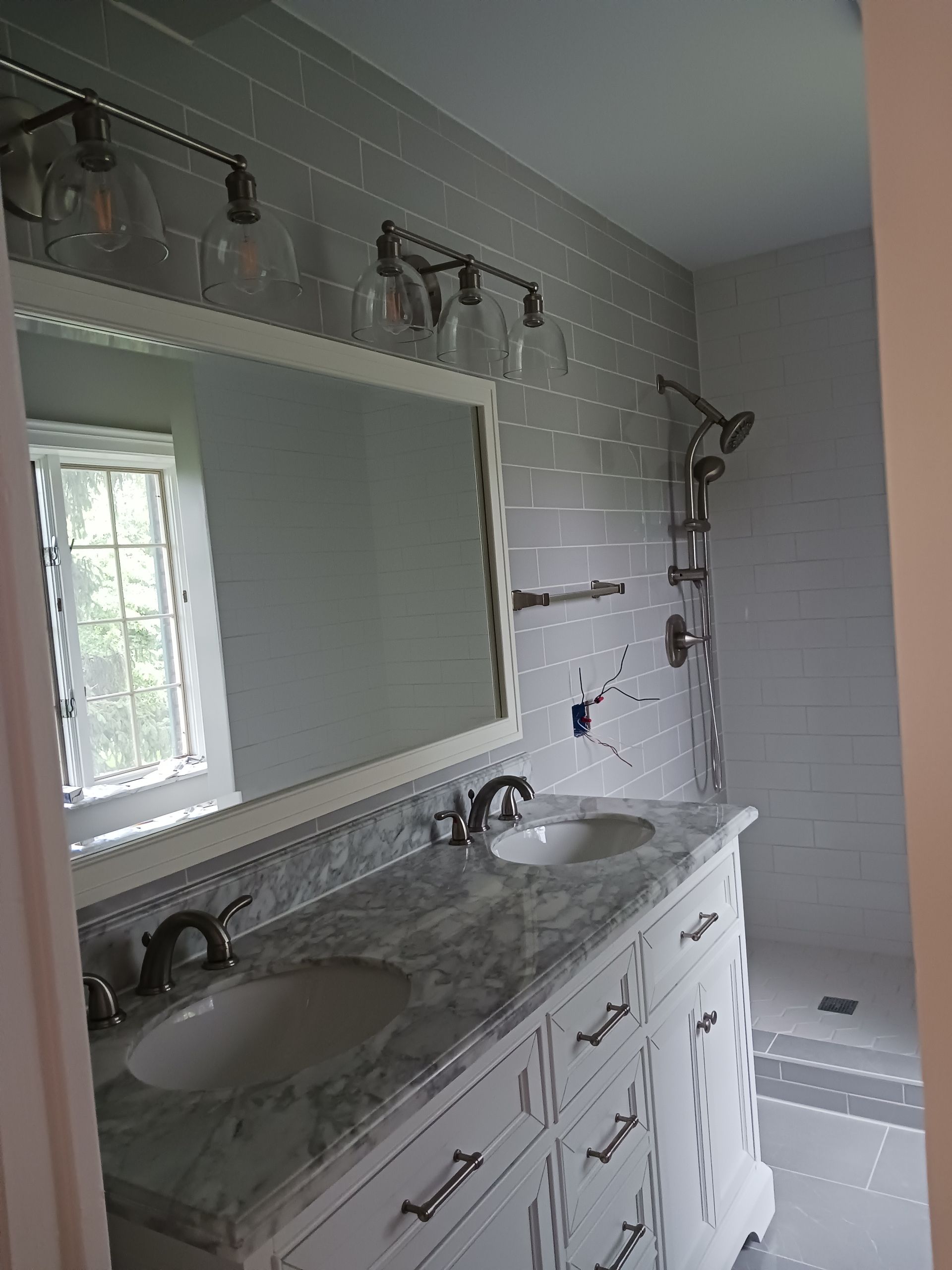 A bathroom with a sink , mirror and shower.