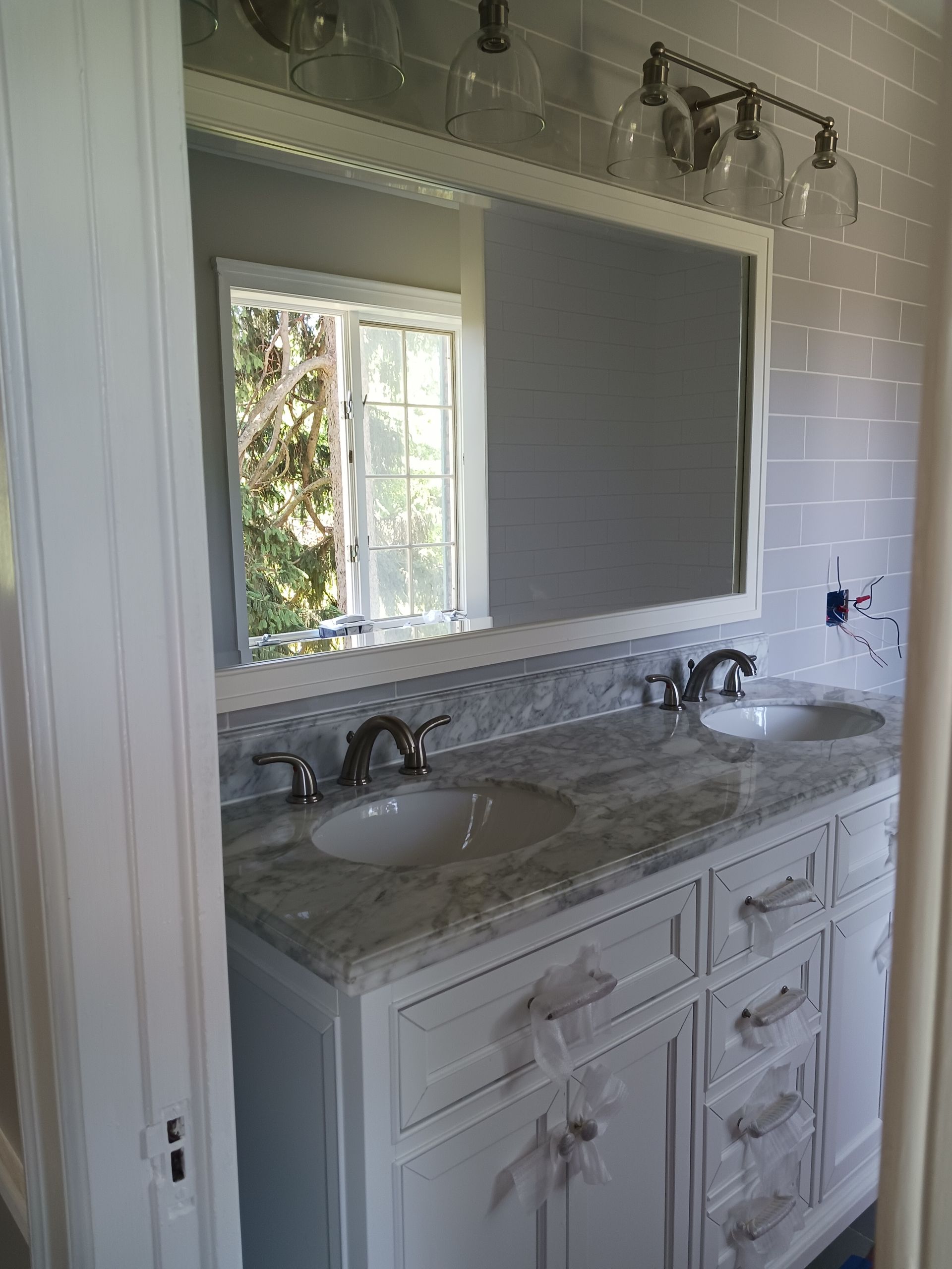 A bathroom with two sinks , a mirror and a window.