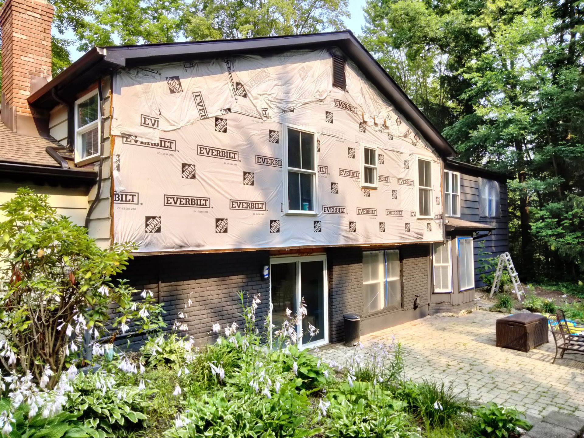 A house with a lot of windows and a patio in front of it.