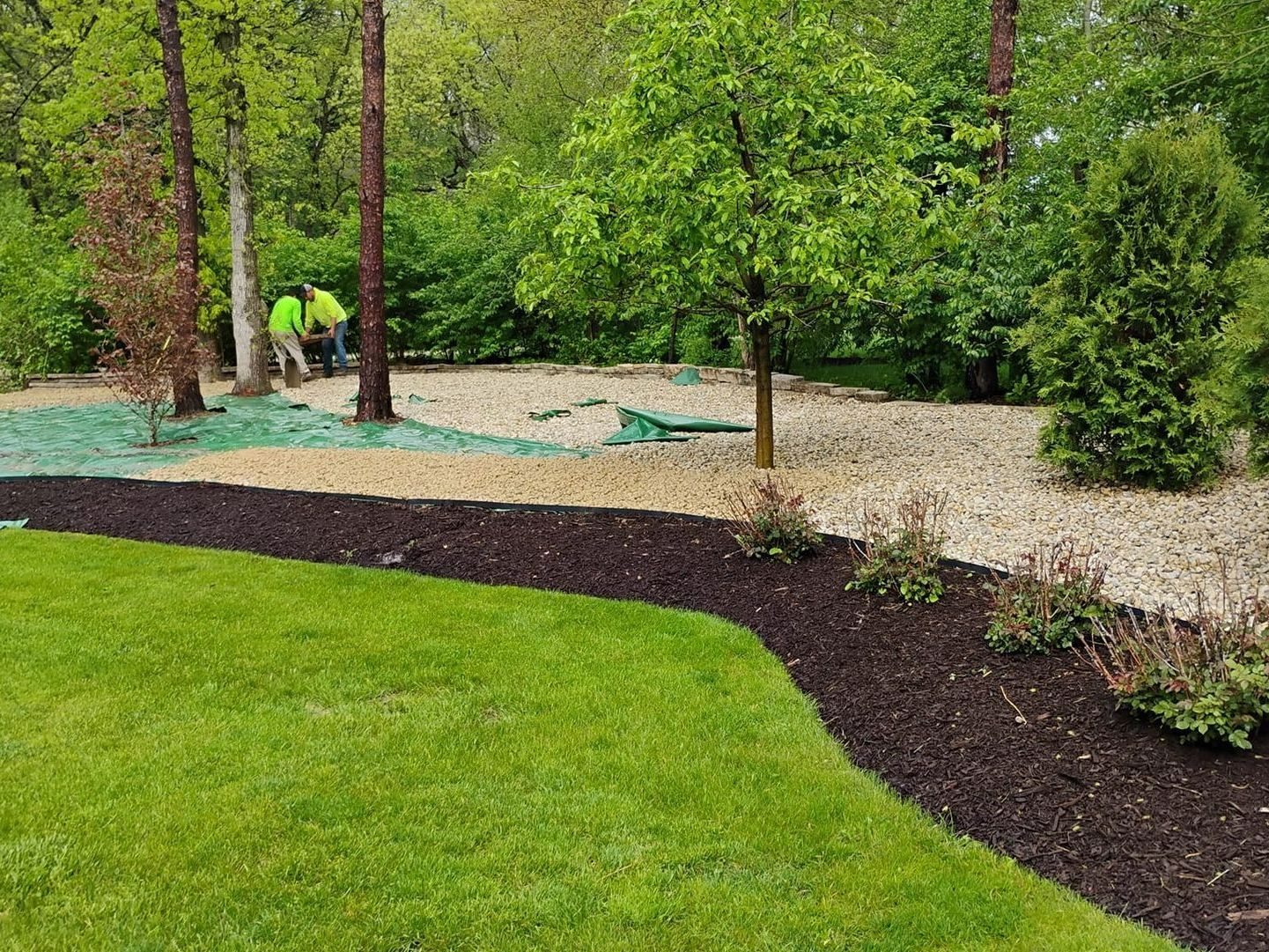 Two men are working on a lush green lawn in a park. Two men are working on a lush green lawn in a park.