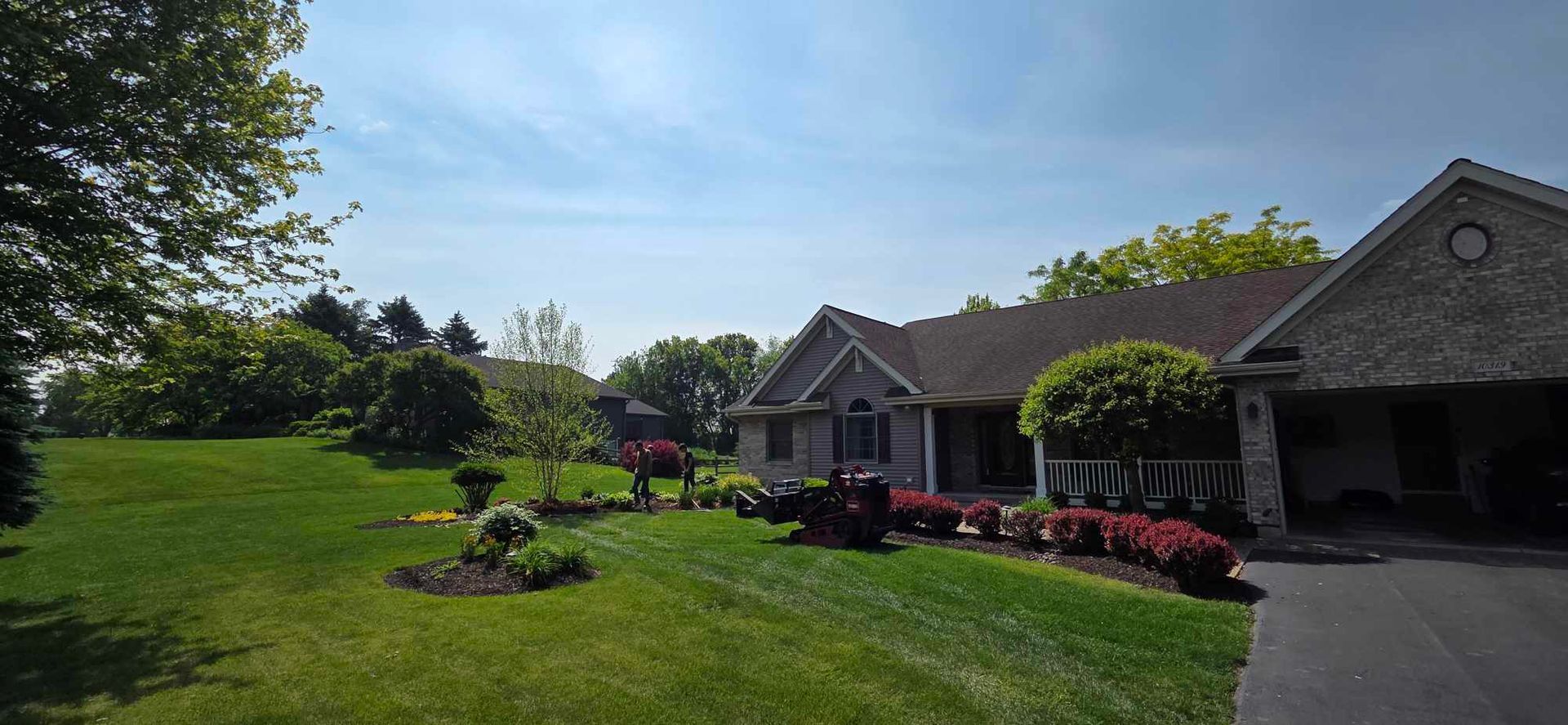 A large house with a lush green lawn and a driveway.