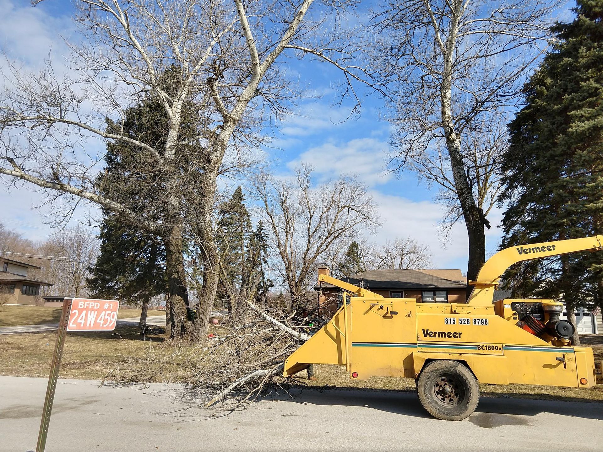 A yellow tree chipper is cutting down a tree. A yellow tree chipper is cutting down a tree.