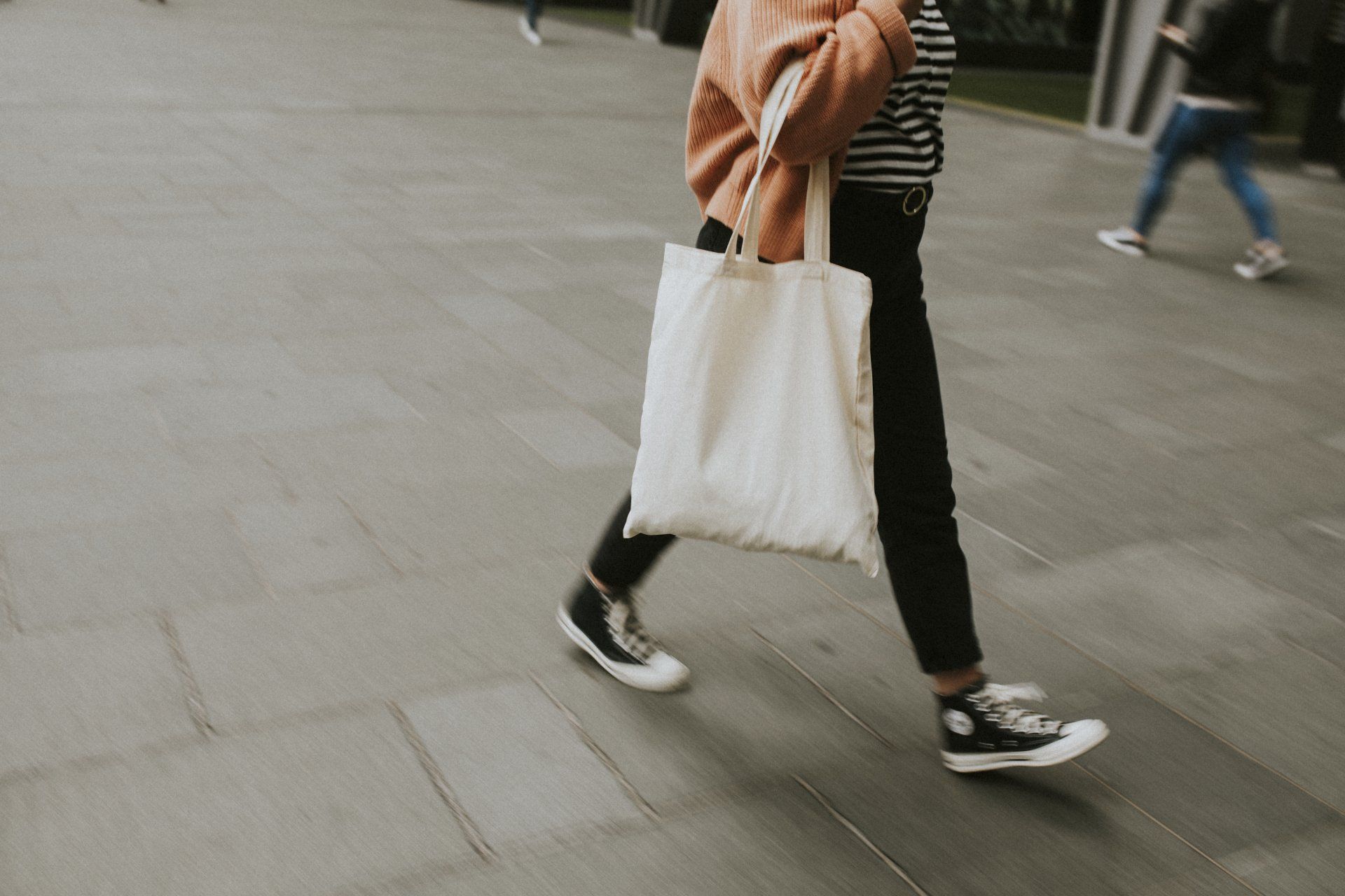 Mujer que lleva la bolsa de asas reutilizable de lona en blanco