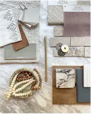 A flat-lay interior design mood board featuring marble, brick, fabric swatches, wood beads, and neutral-toned material.