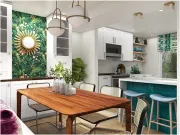 Modern kitchen and dining area with a wooden table, green botanical wallpaper, white cabinets, and a teal kitchen island.