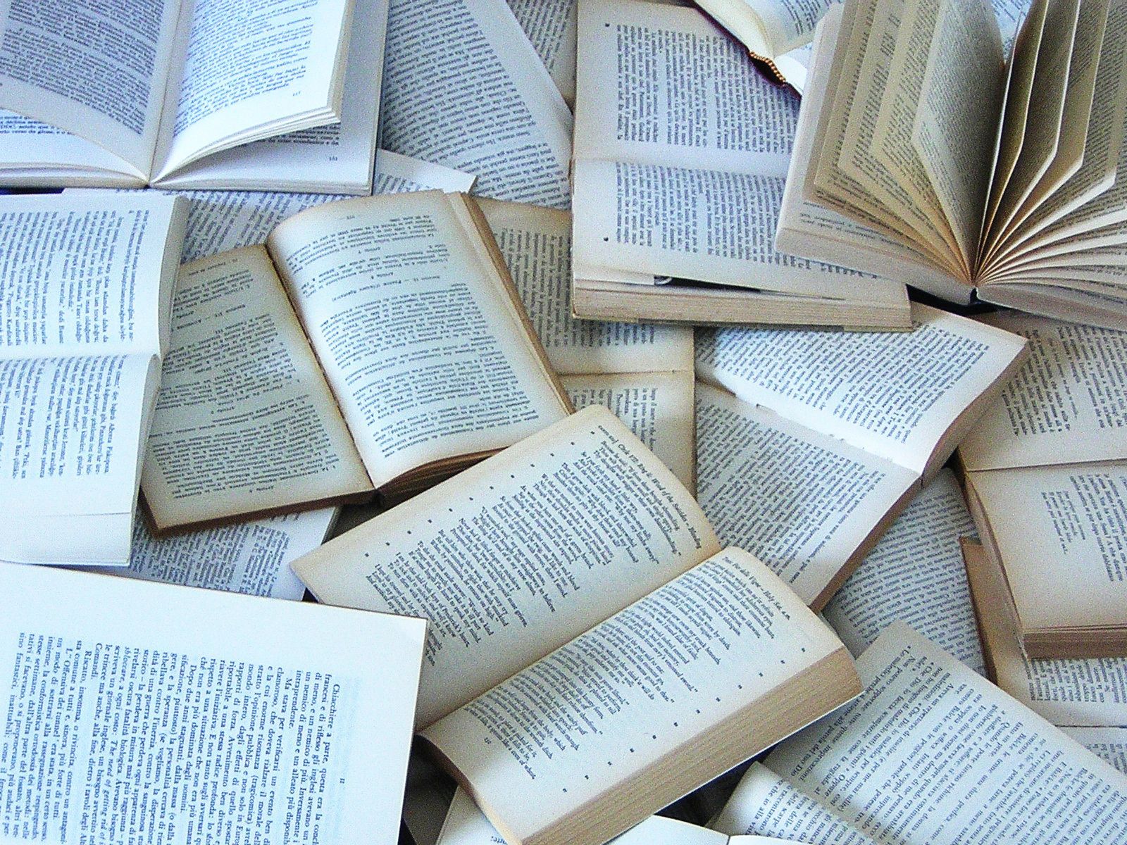 Pile of open books, pages facing up, showing text and edges.