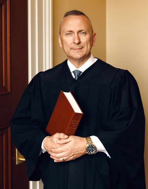 A man in a judge 's robe is holding a bible