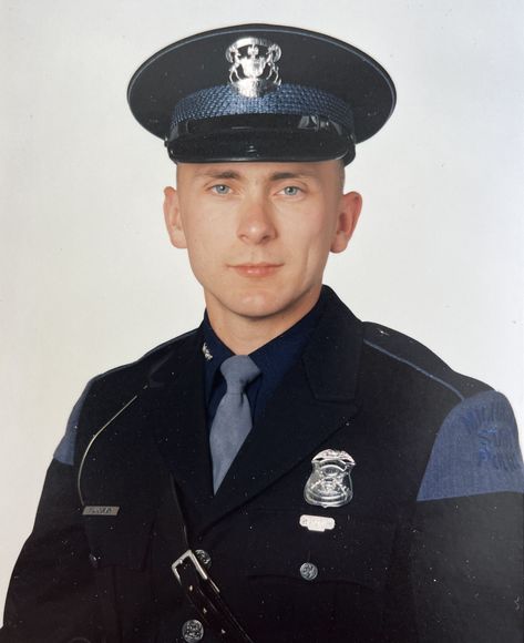 A man in a police uniform with a hat and tie