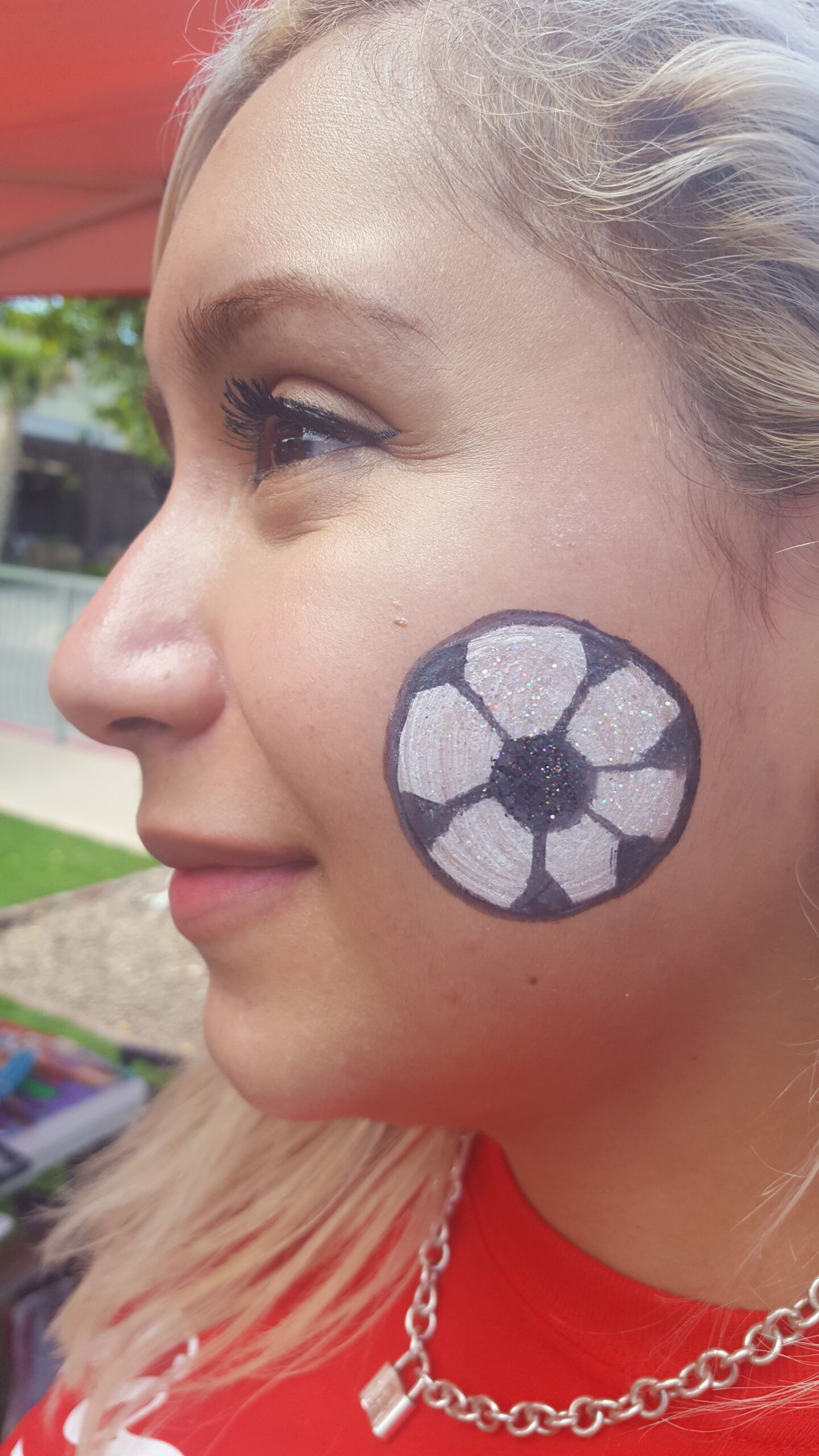 A woman with a soccer ball painted on her face.