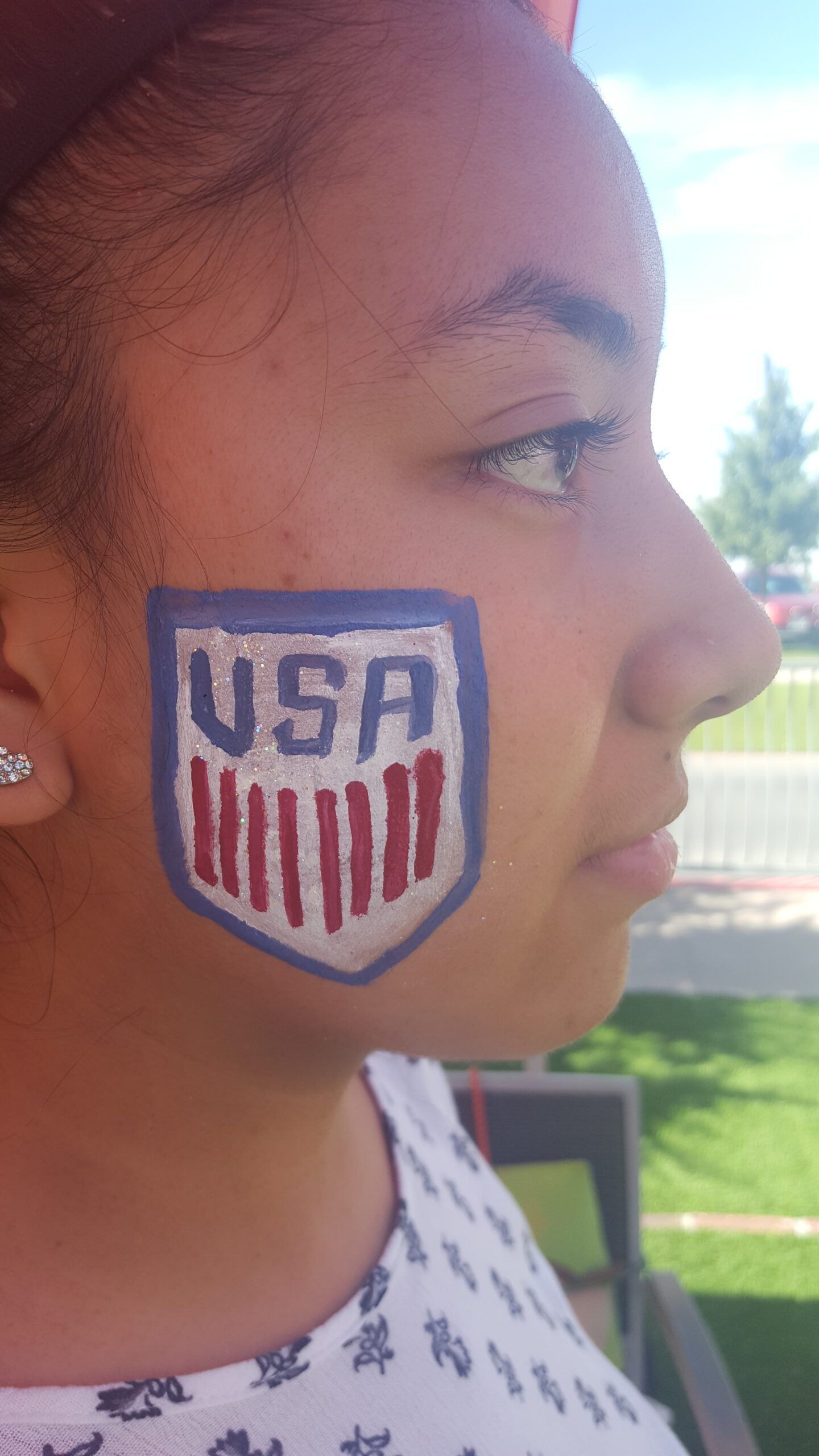 A girl with a usa shield painted on her face.
