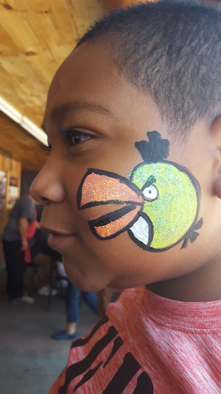 A young boy has an angry bird painted on his face.