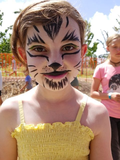 A young girl with her face painted like a cat