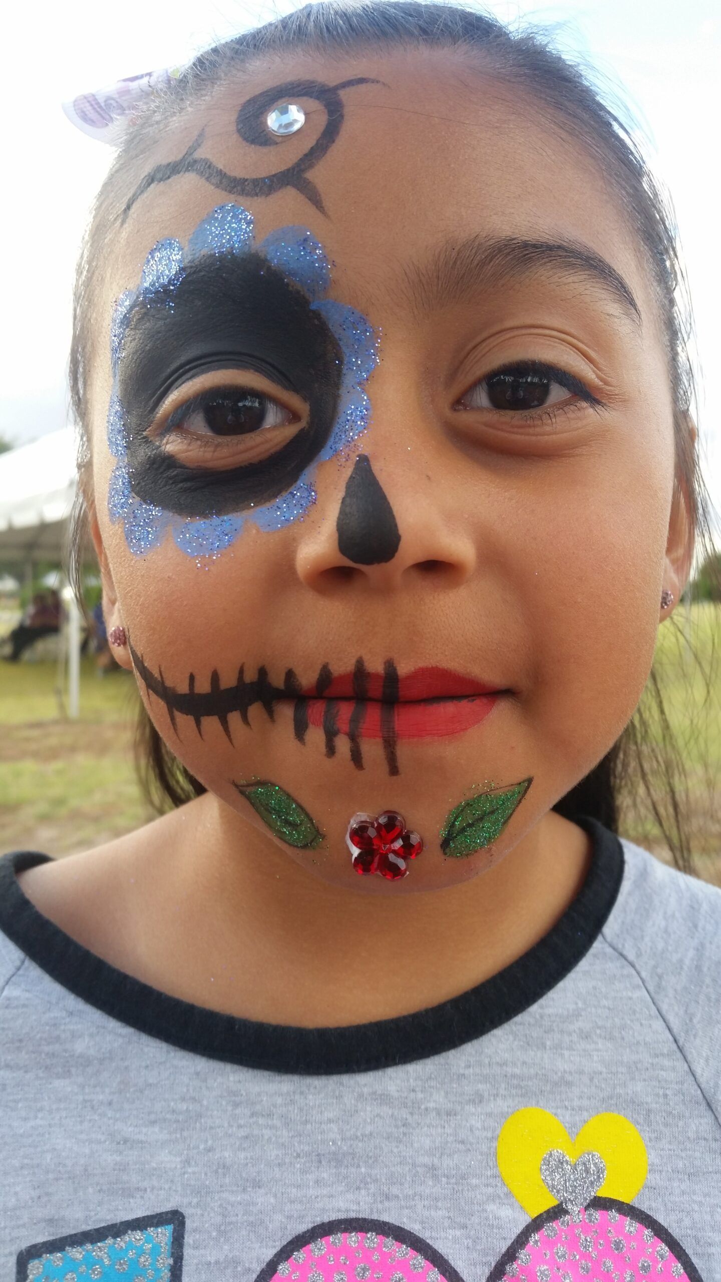 A little girl with her face painted like a skull.