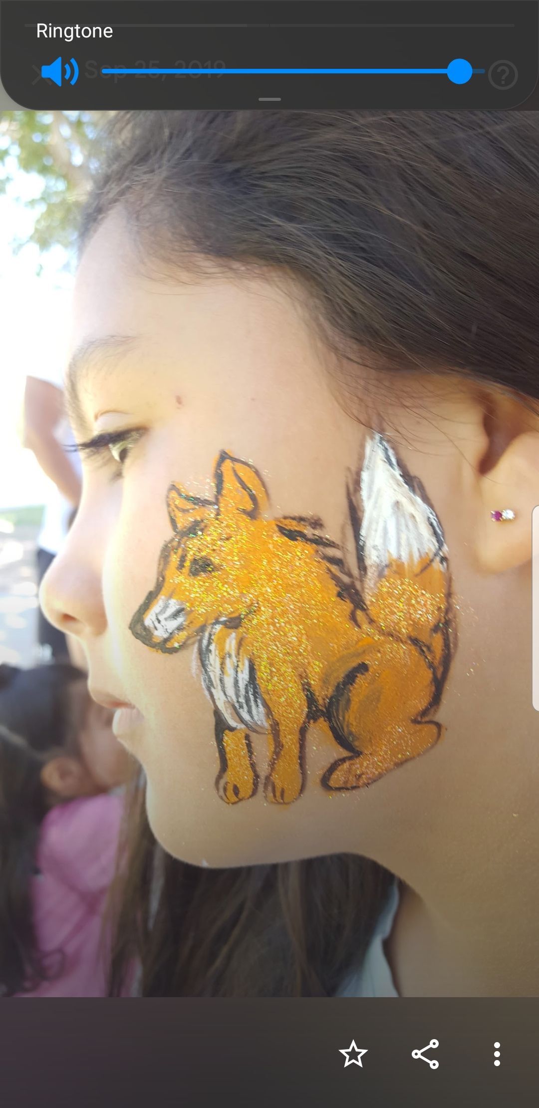 A girl with a fox painted on her face.
