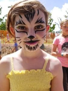 A young girl with her face painted like a cat