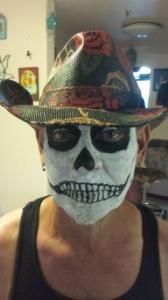 A woman wearing a cowboy hat and a skull face paint.