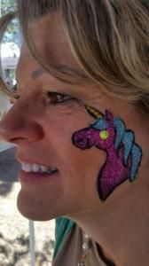 A woman has a unicorn painted on her face.