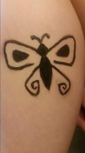 A person has a black butterfly tattoo on their arm.