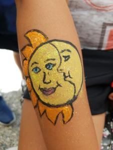 A person has a sun and moon painted on their arm.