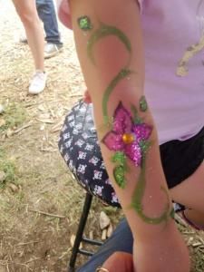 A little girl has a flower painted on her arm.