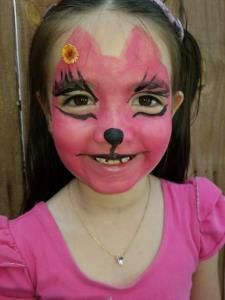A little girl with her face painted like a fox.