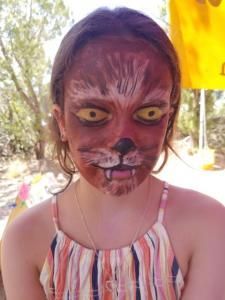 A young girl with her face painted like a cat.