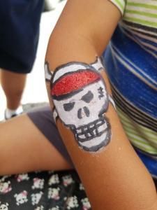 A child has a pirate skull painted on their arm.