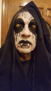 A man in a grim reaper costume is wearing a black hood.