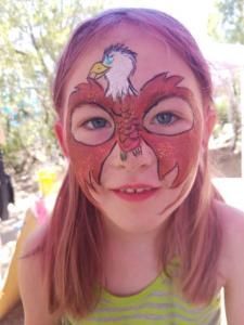 A little girl with her face painted like an eagle.