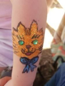A child has a tattoo of a cat on their arm.