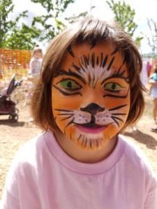 A little girl has her face painted like a tiger