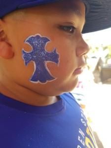 A young boy with a cross painted on his face