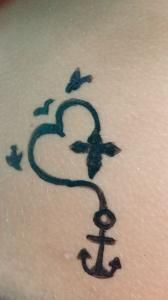 A tattoo of a heart and an anchor on a person 's back.