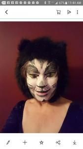 A woman is wearing a cat mask on her face.