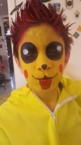 A young boy is wearing a yellow jacket and a pikachu costume.