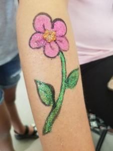 A person has a pink flower painted on their arm.